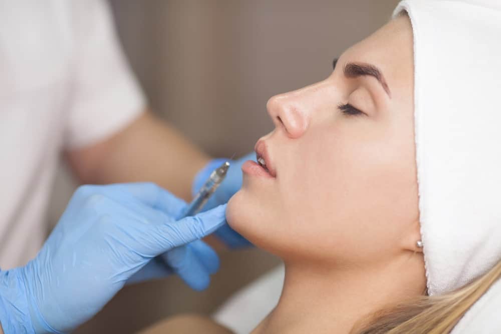 Woman having fillers injected into lips