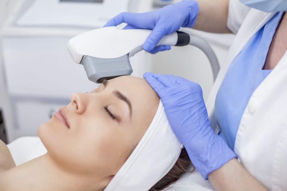 Woman having laser hair removal procedure performed on face